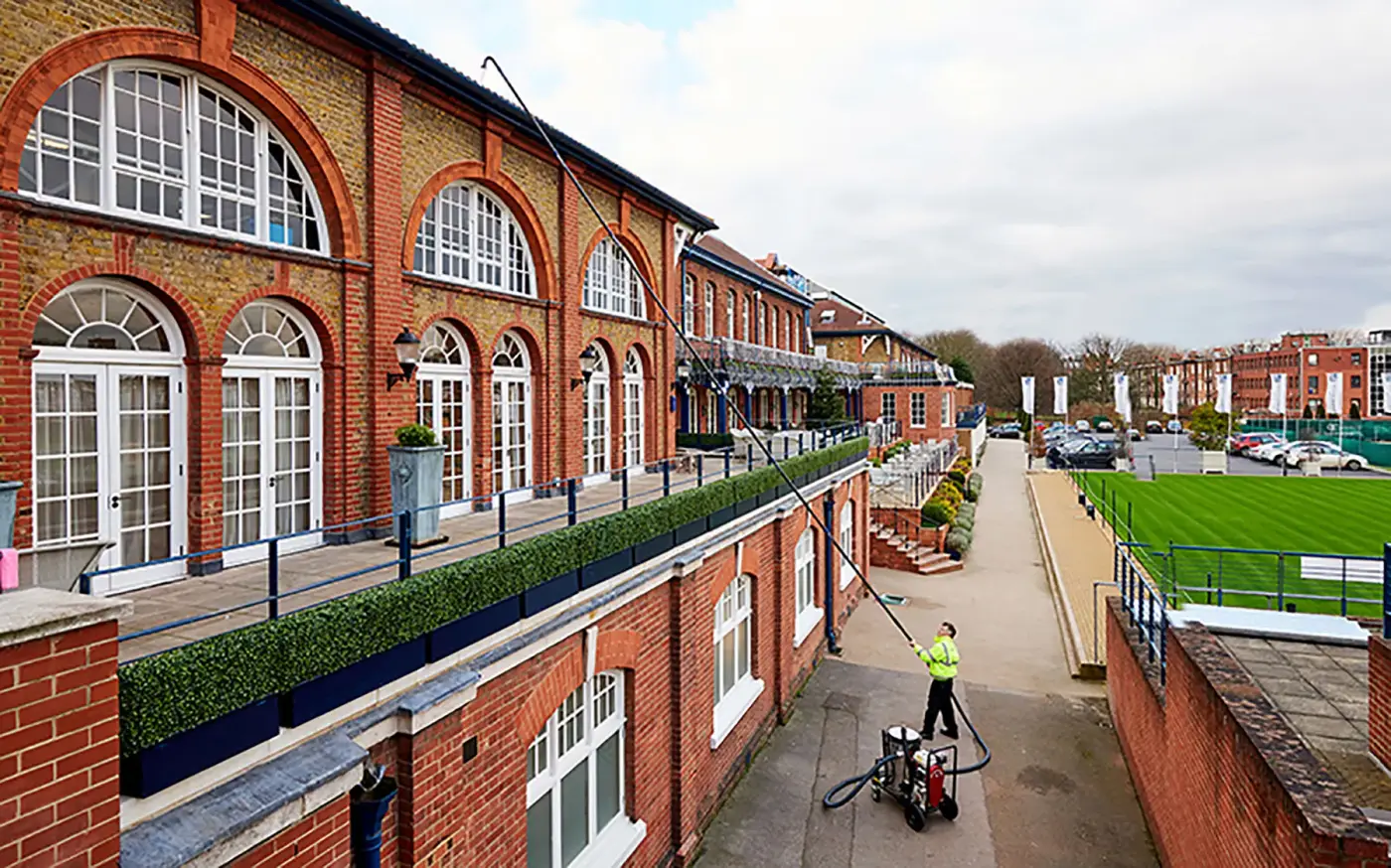 gutter cleaning large building using long pole and gutter vacuum